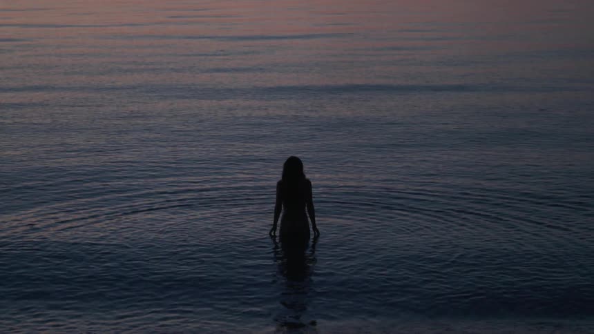 A woman walks naked in the water