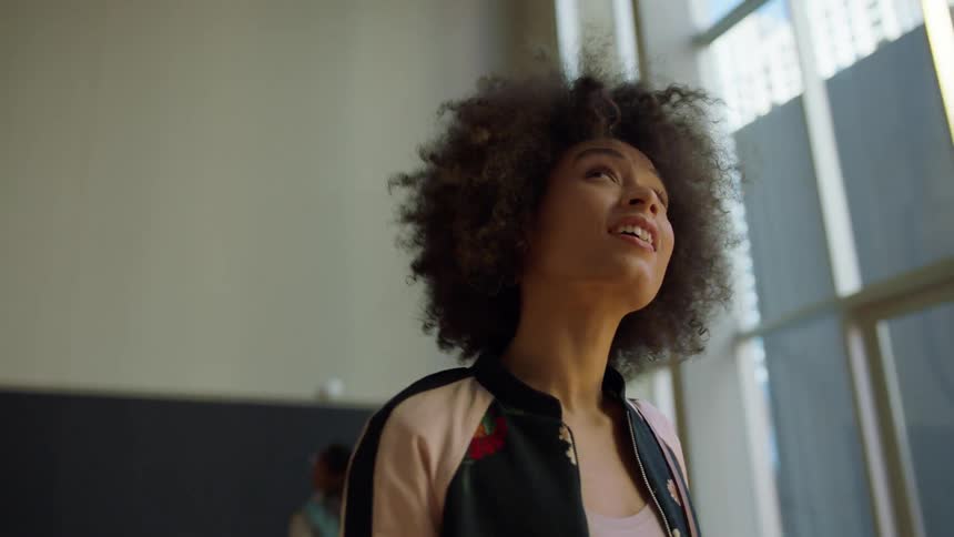 A woman walks around a building looking around