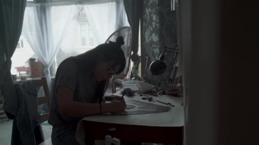 Woman wearing glasses draws at her desk