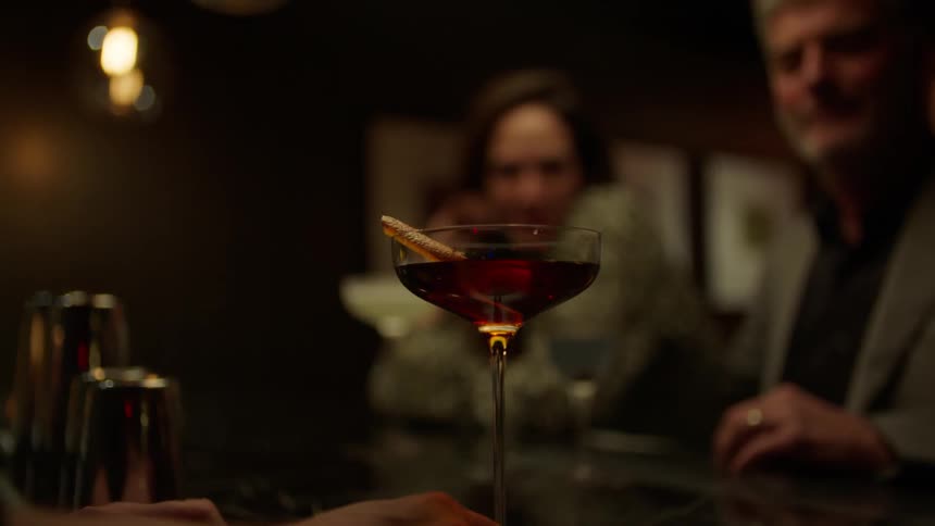 A bartender places a garnish in a drink then delivers it