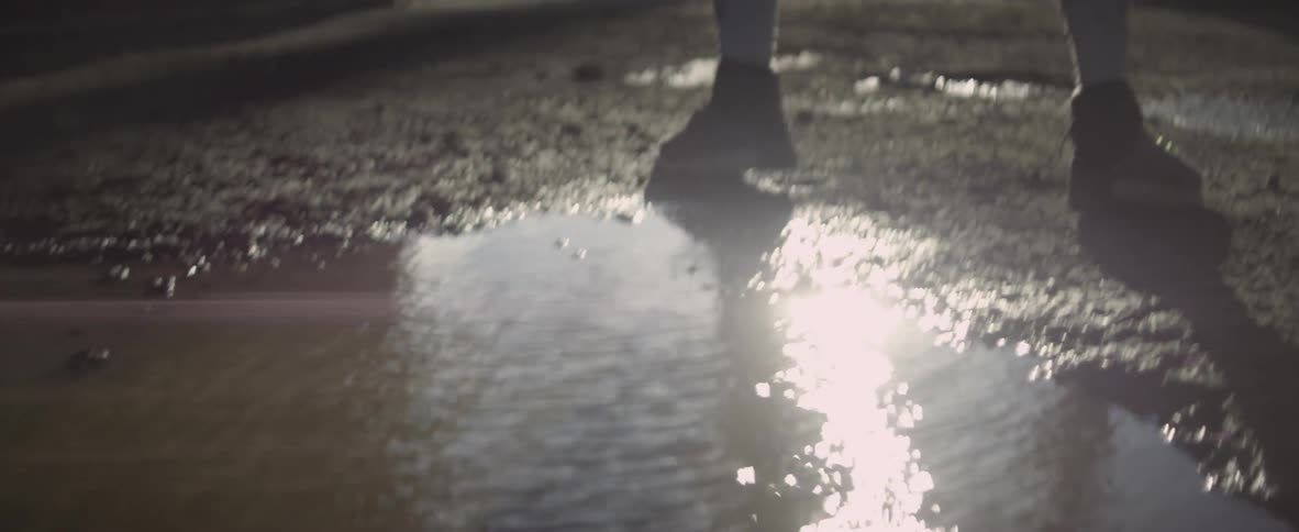 A man dances in front of a rippling puddle