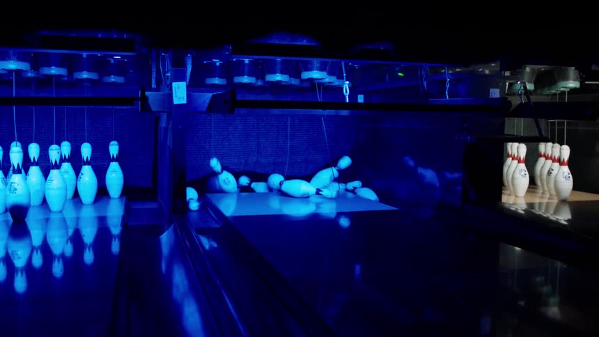 A person makes a strike in the bowling alley