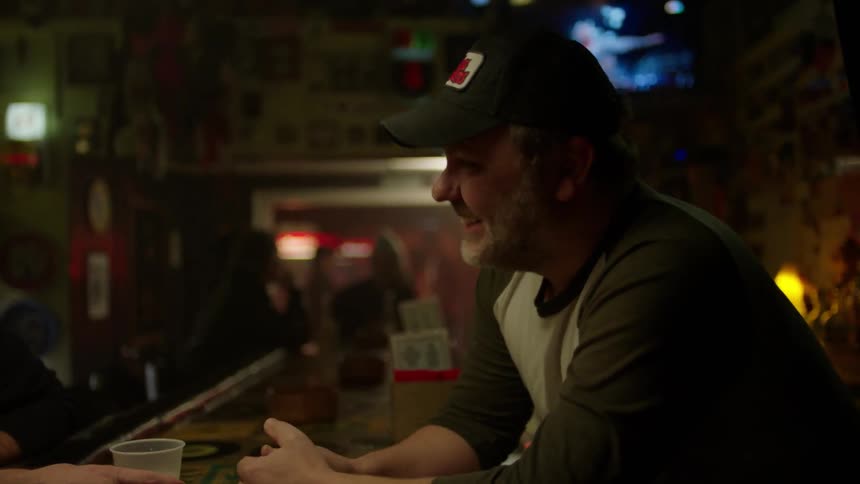 Man wearing a cap talking with his friends in a bar