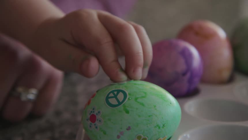 A young girl puts sticks on dyed eggs