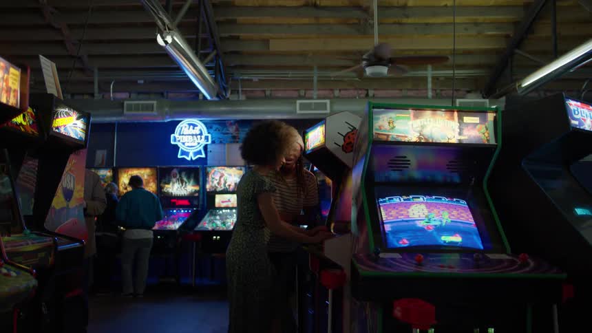 Man and woman laugh and play a game in an arcade