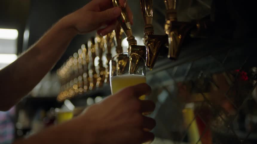 A person pours a beer from a tap
