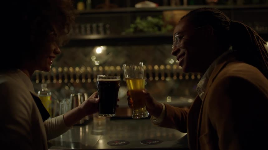 A man and woman toast at a bar