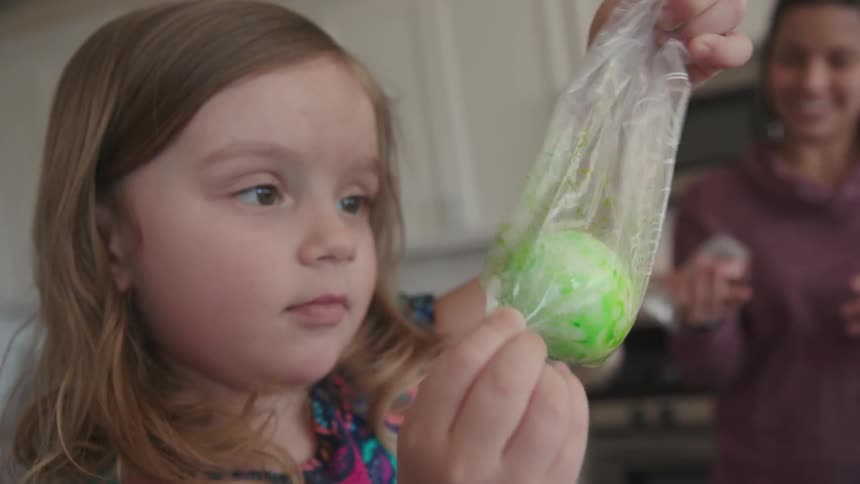 A mother and daughter are dying eggs in bags