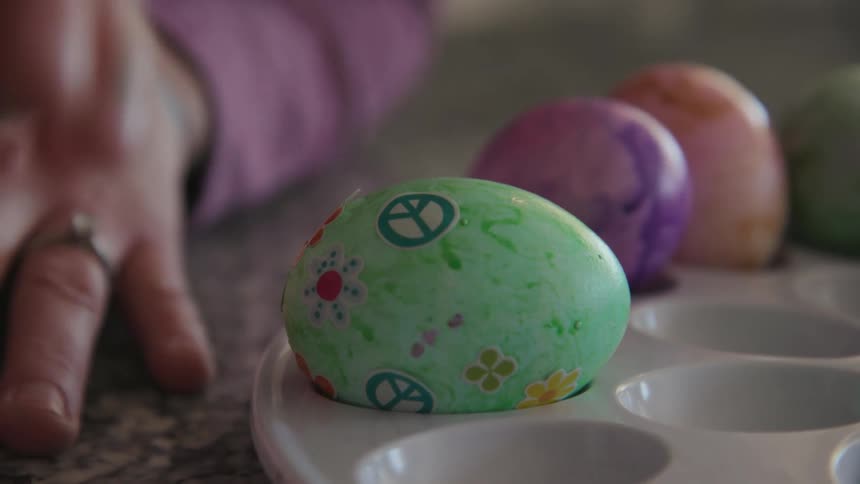 A young girl puts stickers on dyed eggs