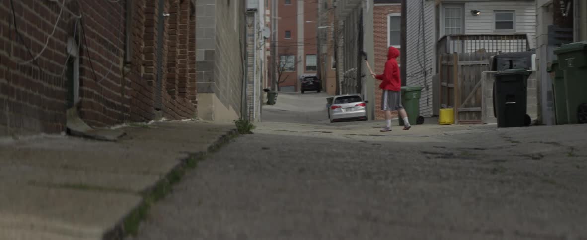 A man is tossing a ball at a wall with a lacrosse stick