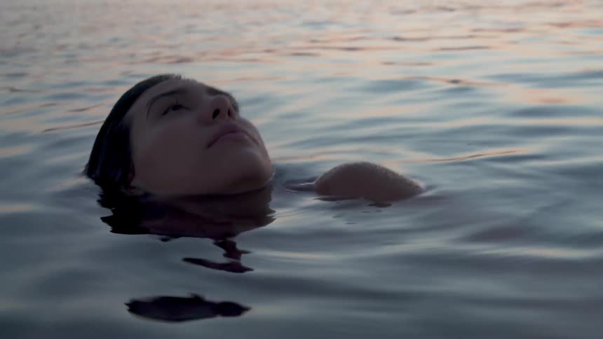 Woman floating in lake water after sunset