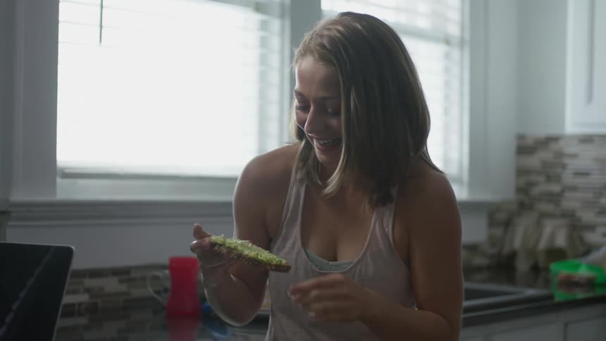 Woman smiles as she eats a piece of toast