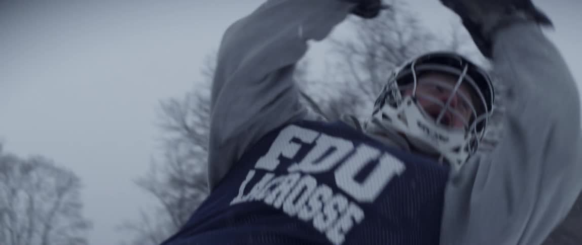 A lacrosse player swings for the ball as it snows