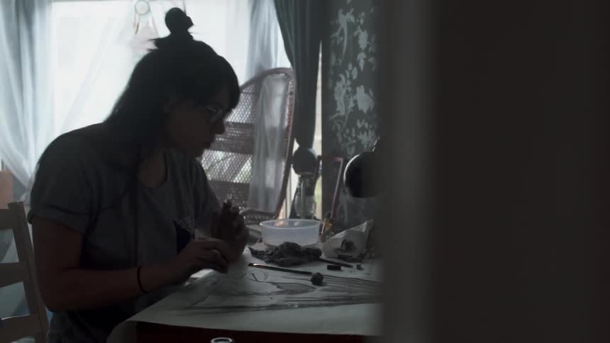 A woman sits at a desk sketching