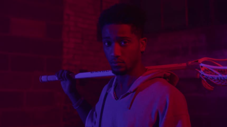 A man holds a lacrosse stick over his shoulder