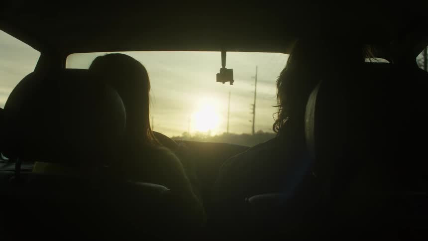 Two people are driving down the road at sunset