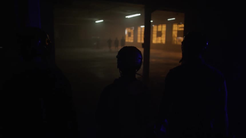 Several people wearing helmets walk into a large area