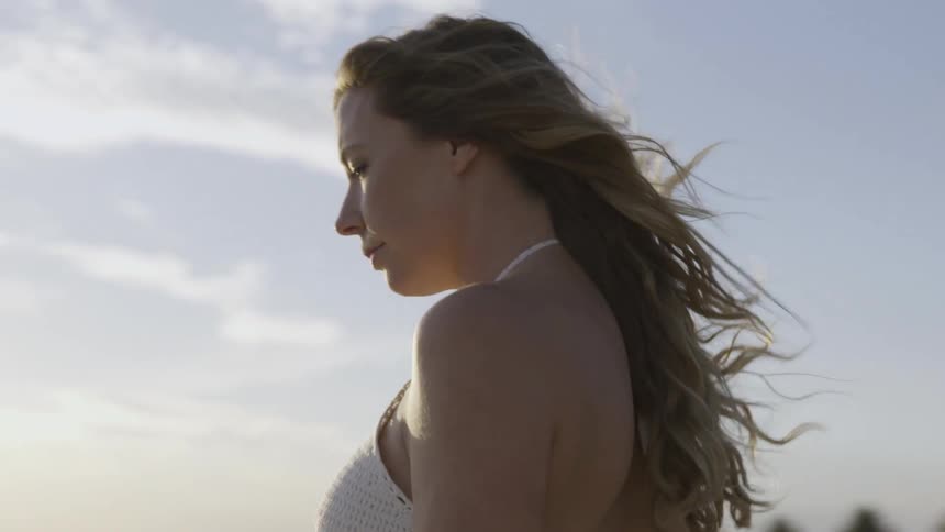 Woman wearing a white halter top while walking outdoors on a cloudy day