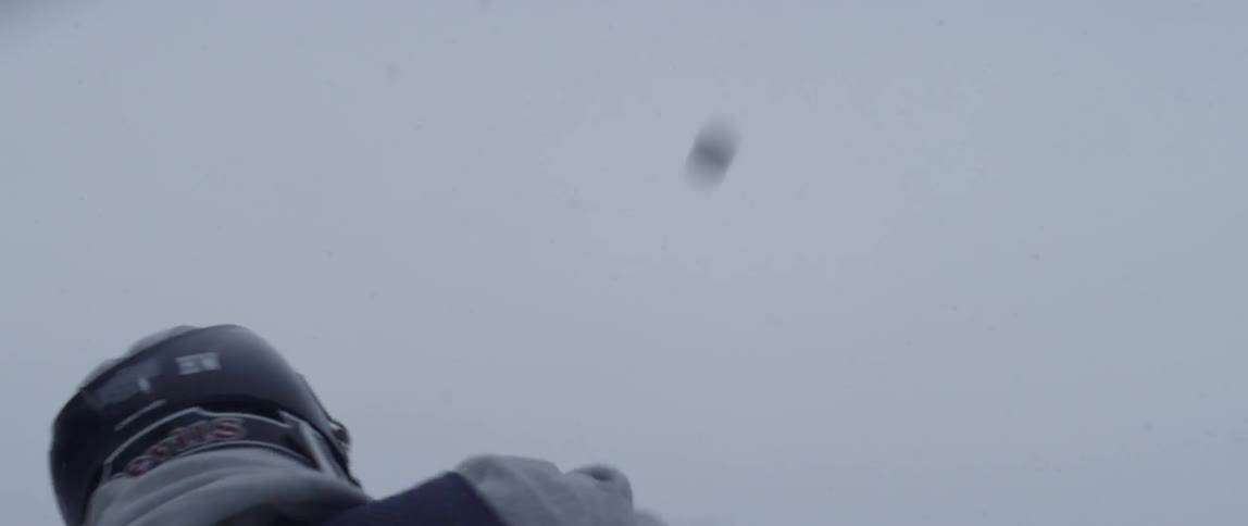 A man out in the snow shoots a lacrosse ball