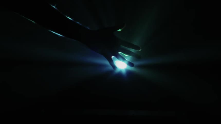 A man sticks his hand out in front of a blue light