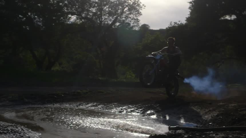 A man jumps a mud puddle on a dirt bike