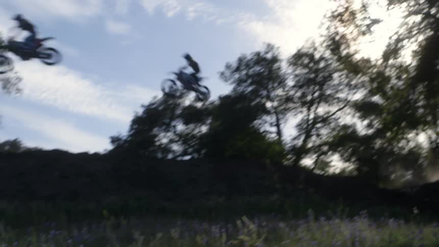 People on dirt bikes fly high in the air over the trees