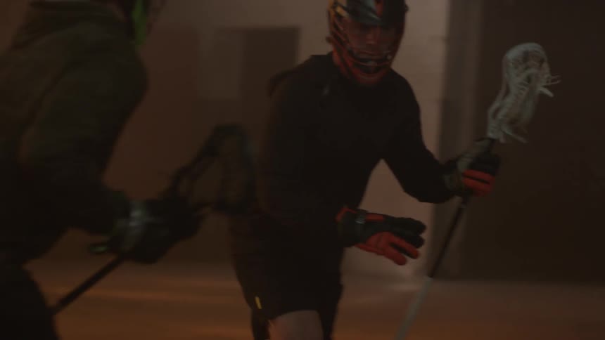 Man playing lacrosse dodges opposing team member and runs