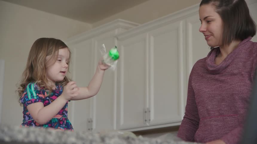 A mom and young girl dye easter eggs in a kitchen