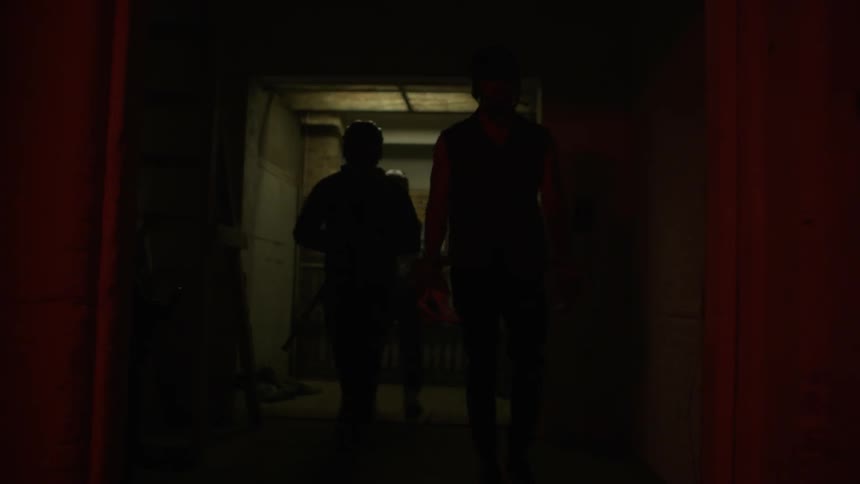 Men in lacrosse gear open a gate and walk through a dark building