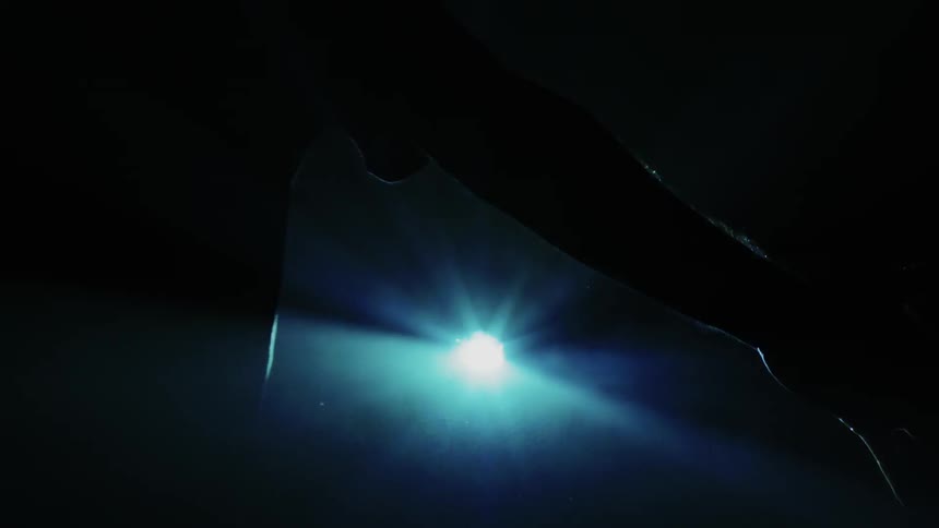 A man stands with his arm outstretched in front of a pulsing light