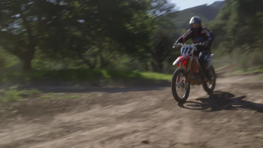 A man rides a dirt bike on a dirt trail