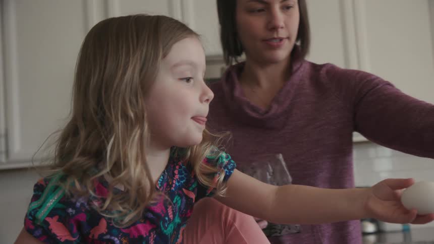 A woman helps a young girl dye eggs