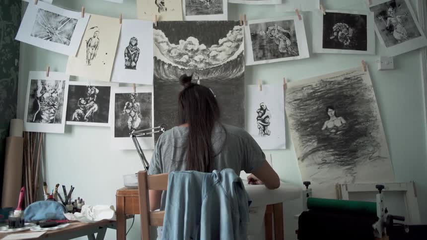 An artist sits at a desk sketching