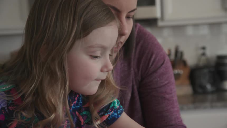 A mom and young girl work in a kitchen at home