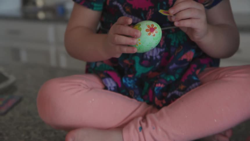 A mother and child are decorating dyed eggs