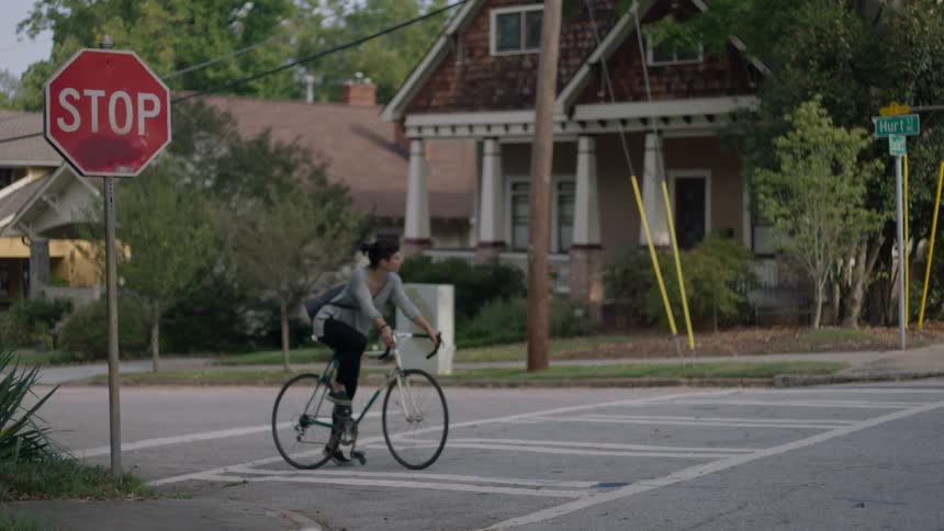 A woman stops at the stop sign on her bicycle before proceeding