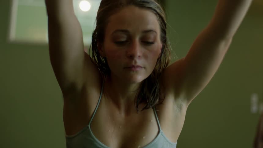 A woman in a yoga studio stretches down over her legs