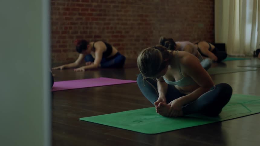 Group of women stretch on mats in a studio