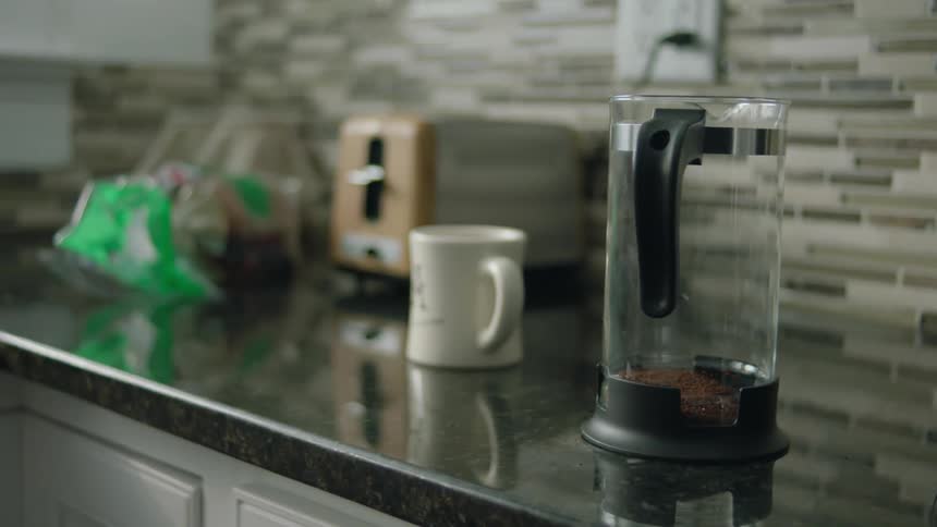 A coffee press canister sits on a kitchen countertop