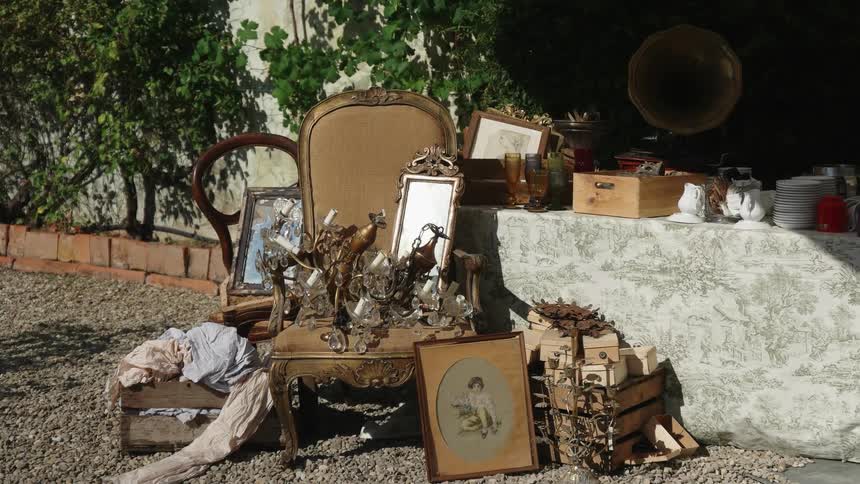 Antique furniture and items are stacked outside of the house