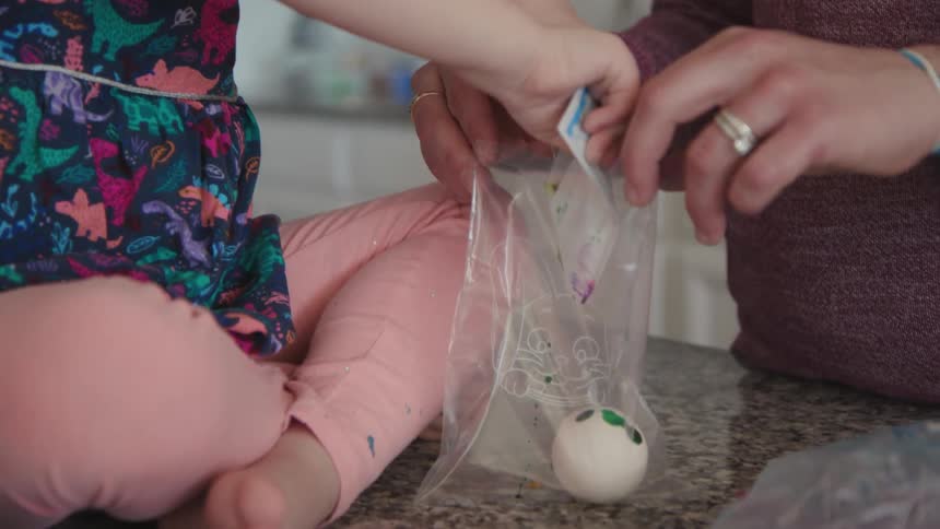 A girl and mother dye easter eggs