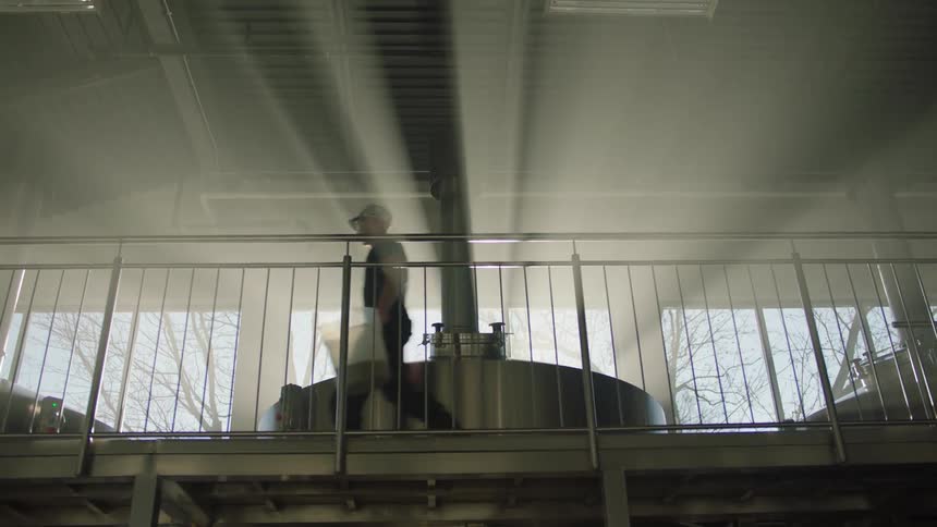 A man walks past vats in a warehouse