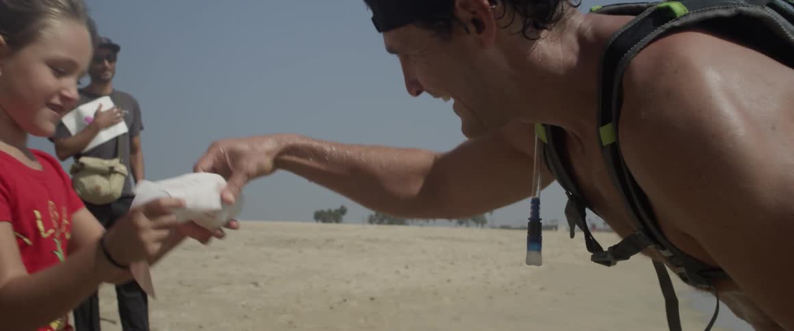 A man kisses a young girl on a sandy beach