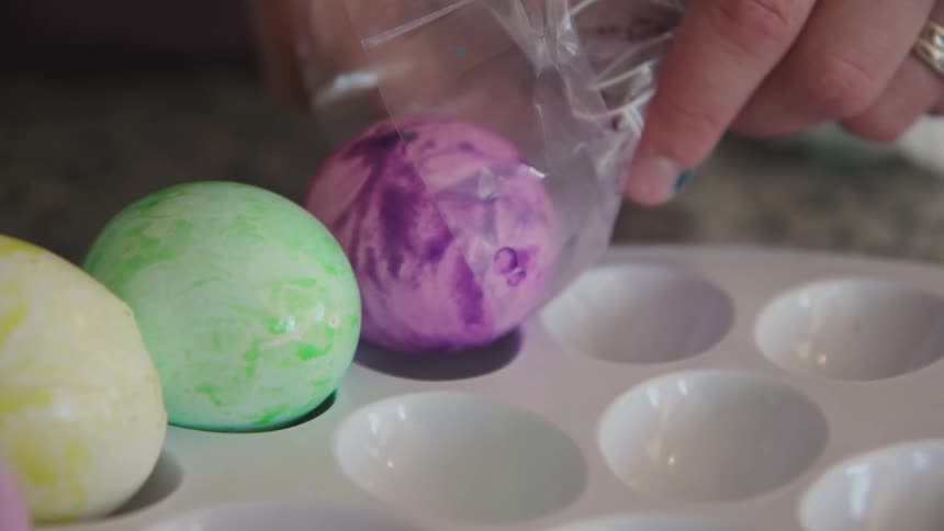 Person drops colored egg onto a small tray