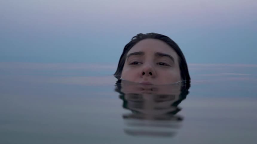 A woman is floating in the water on a cloudy day