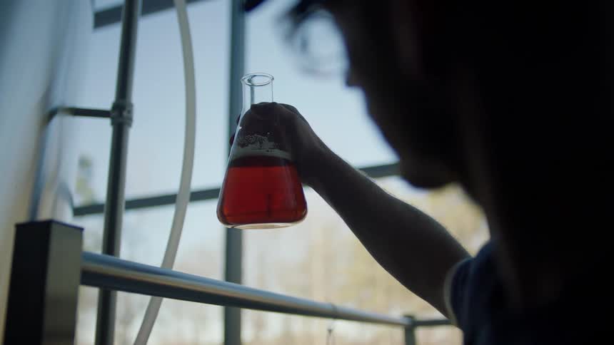 A man examines a liquid in a glass beaker