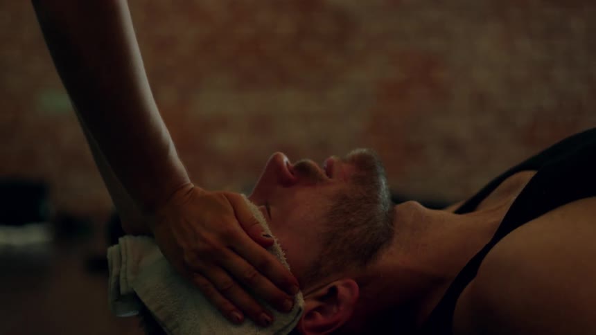 A person places a wet cloth on a man's head