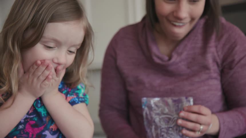 A woman helps a young girl dye eggs