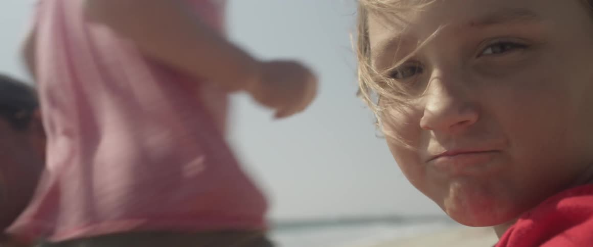 A man and some children are spending time on the windy beach