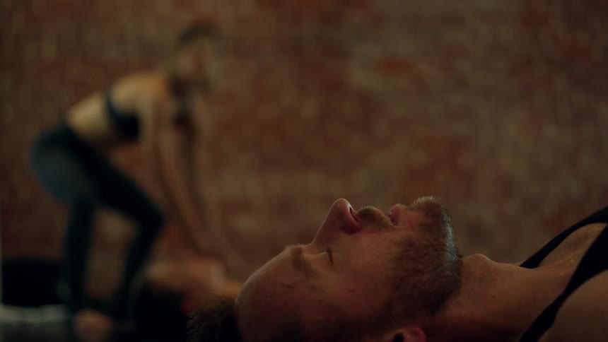 A man lies with his eyes closed in a yoga class